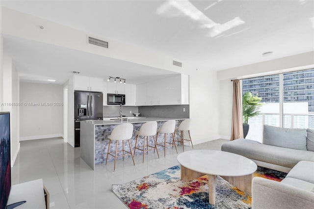 living room featuring light tile patterned floors, visible vents, and baseboards