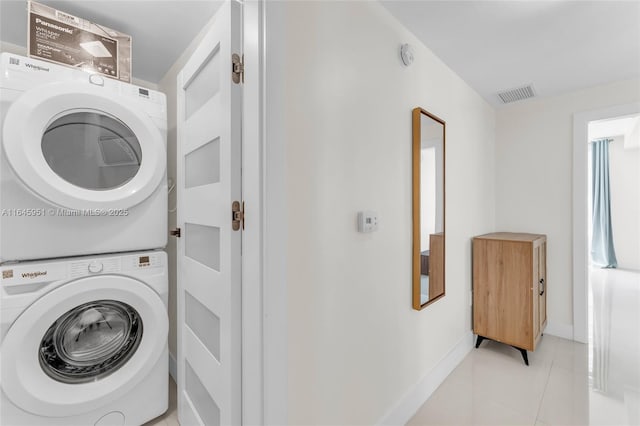 clothes washing area with laundry area, light tile patterned floors, visible vents, stacked washer / dryer, and baseboards
