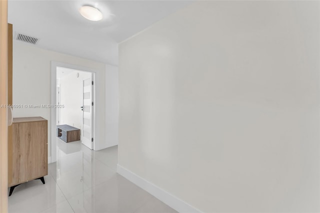 hall featuring visible vents, baseboards, and light tile patterned flooring