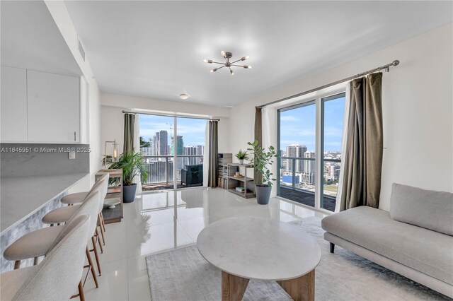 living room featuring light tile patterned floors, plenty of natural light, a notable chandelier, and a city view