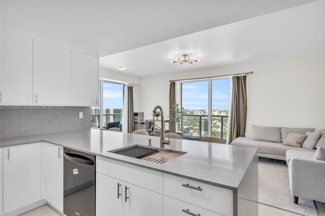 kitchen with a peninsula, dishwasher, a sink, open floor plan, and decorative backsplash