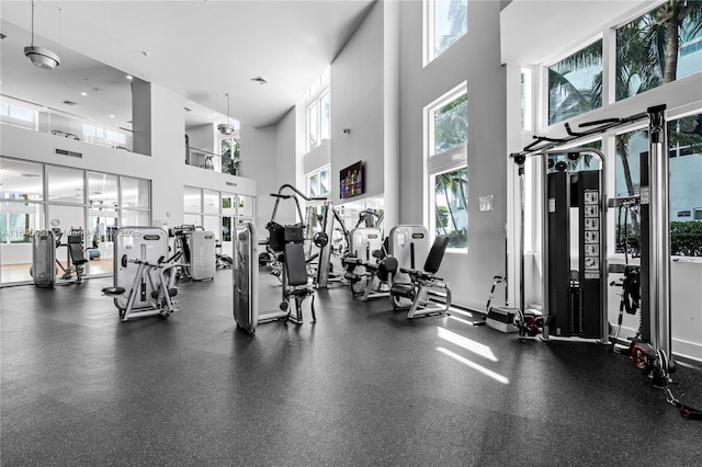 workout area with visible vents, a towering ceiling, and plenty of natural light
