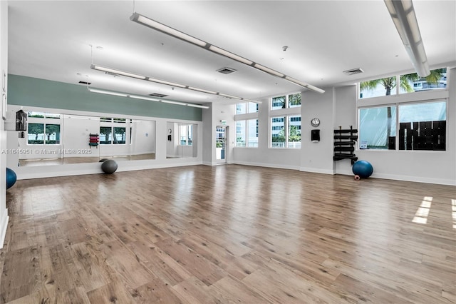 workout area with visible vents, baseboards, and wood finished floors