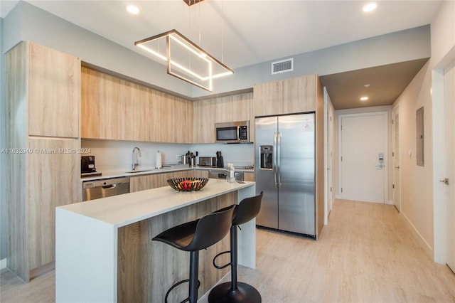 kitchen featuring a kitchen bar, a center island, light hardwood / wood-style floors, stainless steel appliances, and pendant lighting