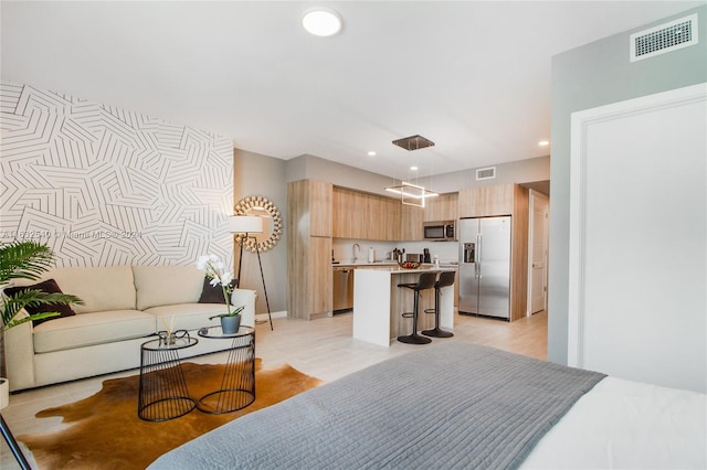 bedroom with sink, stainless steel fridge with ice dispenser, and light hardwood / wood-style floors