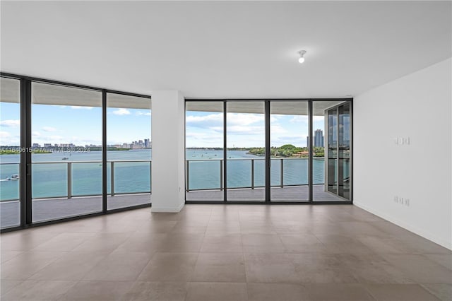 empty room with expansive windows, a water view, and plenty of natural light