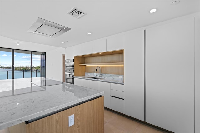 kitchen with white cabinets, a water view, sink, and black electric stovetop