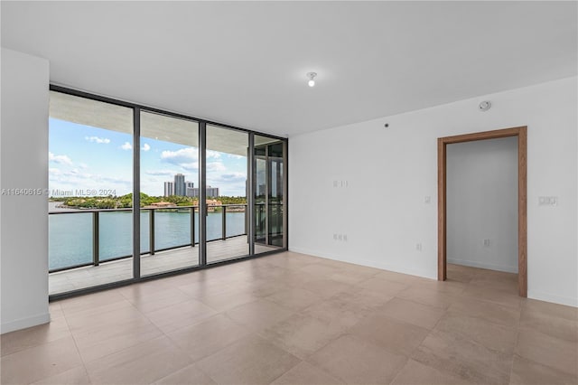 unfurnished room featuring a water view and a wall of windows