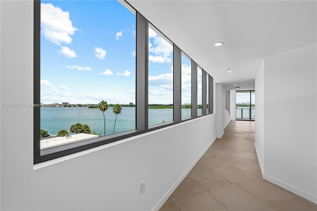 hall with light tile patterned floors, a water view, and plenty of natural light