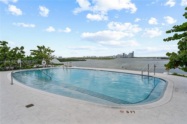 view of pool with a water view and a patio