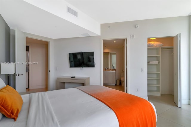 tiled bedroom with a closet, a spacious closet, and connected bathroom