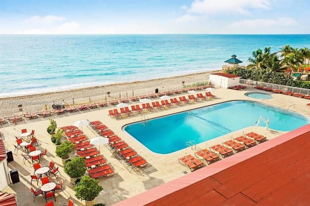 view of pool with a beach view, a patio area, and a water view