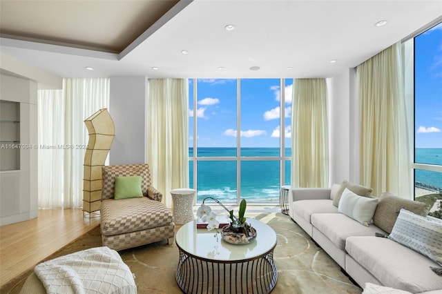 living room featuring a water view, expansive windows, wood finished floors, and recessed lighting