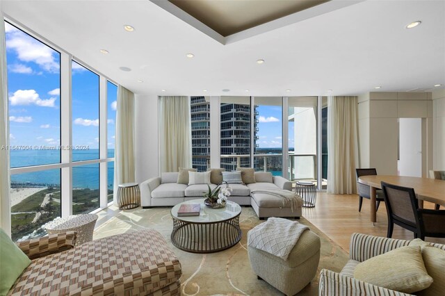 living room with light wood-type flooring, plenty of natural light, a wall of windows, and a water view