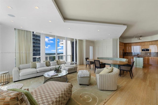 living room featuring a wall of windows, recessed lighting, and light wood-style flooring