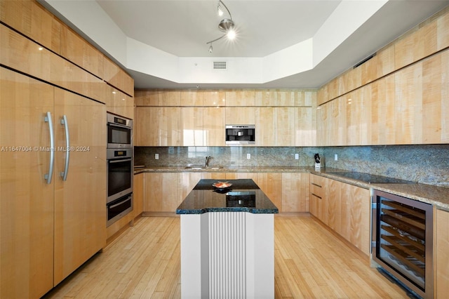 kitchen with light wood-type flooring, wine cooler, rail lighting, a kitchen island, and a raised ceiling