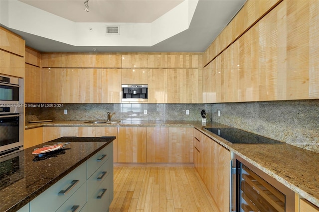 kitchen with light wood-type flooring, backsplash, stainless steel double oven, wine cooler, and dark stone countertops