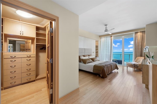 bedroom featuring a water view, ceiling fan, light wood-style flooring, and access to outside