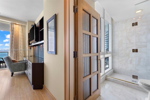 hall with a wealth of natural light, tile walls, and light tile patterned floors