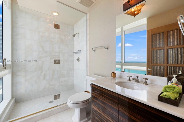 bathroom featuring vanity, tile patterned floors, a water view, a tile shower, and toilet