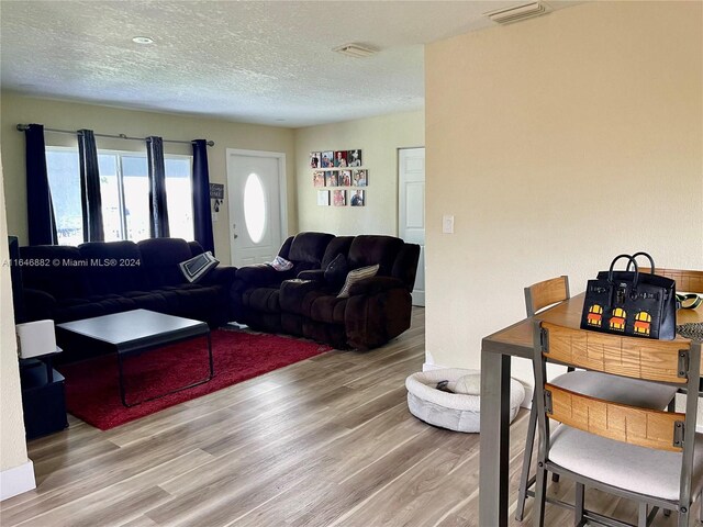 living room with a textured ceiling and wood-type flooring