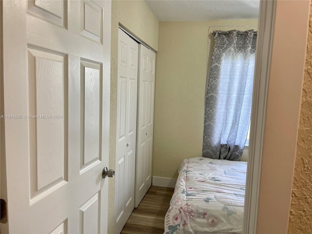 bedroom with a closet, baseboards, and wood finished floors