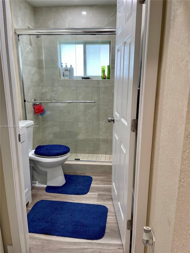 bathroom with toilet, a shower stall, and wood finished floors