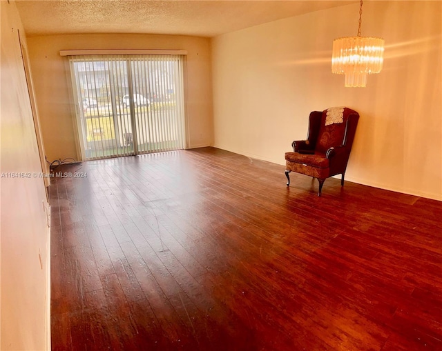 unfurnished room featuring a chandelier, a textured ceiling, and hardwood / wood-style flooring