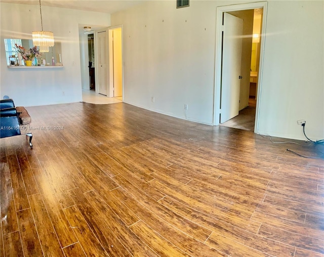 unfurnished living room featuring wood-type flooring and a notable chandelier