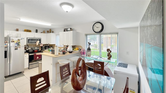 3395 NE 9th St Unit 101, Homestead, FL 33033 - kitchen featuring stainless steel appliances, light countertops, white cabinetry, light tile patterned floors, and a peninsula