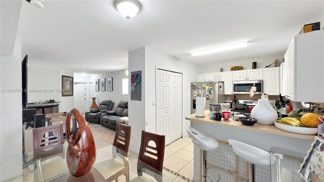 3395 NE 9th St Unit 101, Homestead, FL 33033 - kitchen featuring stainless steel appliances, white cabinets, light tile patterned flooring, a peninsula, and a kitchen breakfast bar
