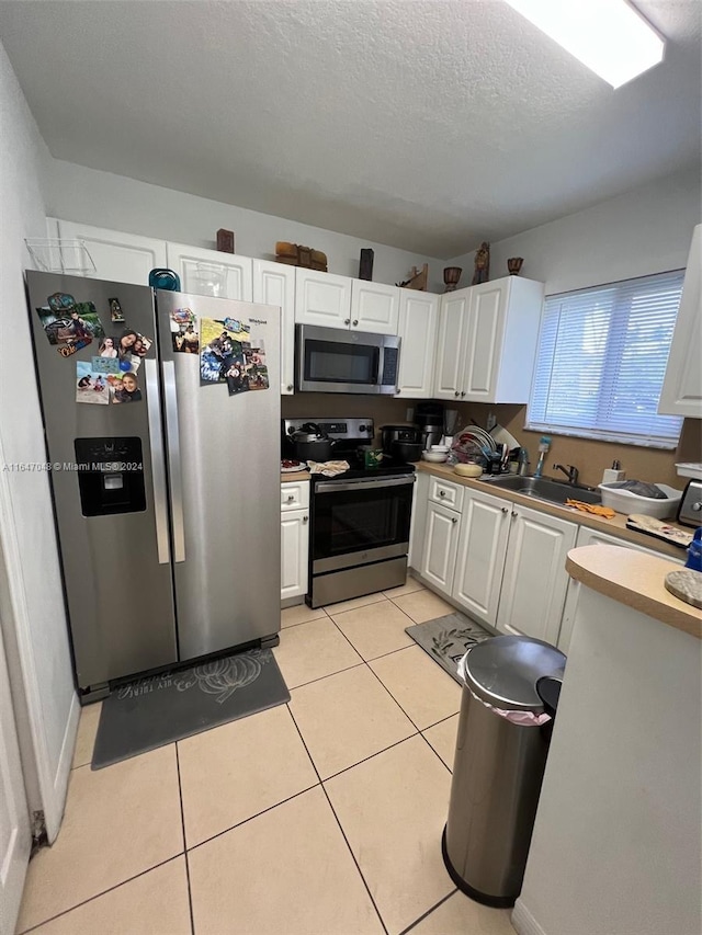 3395 NE 9th St Unit 101, Homestead, FL 33033 - kitchen featuring appliances with stainless steel finishes, a sink, white cabinets, light tile patterned floors, and a textured ceiling