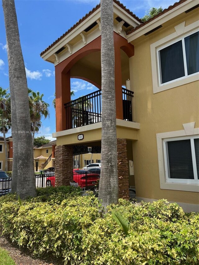 3395 NE 9th St Unit 101, Homestead, FL 33033 - rear view of house featuring stucco siding, a balcony, a tiled roof, and fence