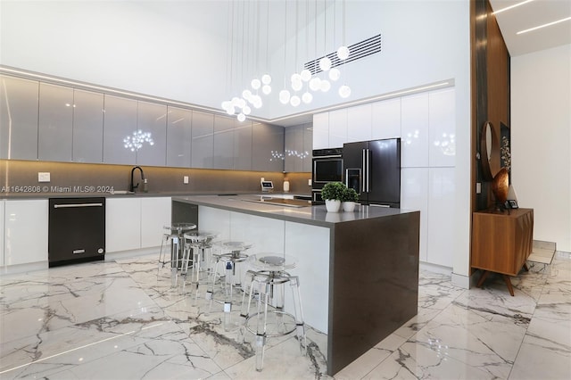 kitchen featuring black appliances, white cabinetry, a high ceiling, pendant lighting, and decorative backsplash