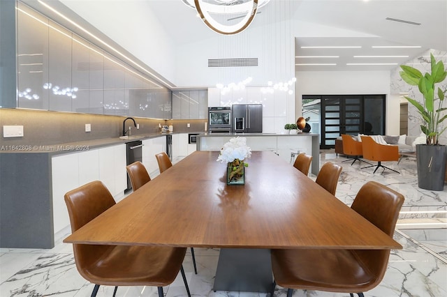 dining room featuring sink and high vaulted ceiling