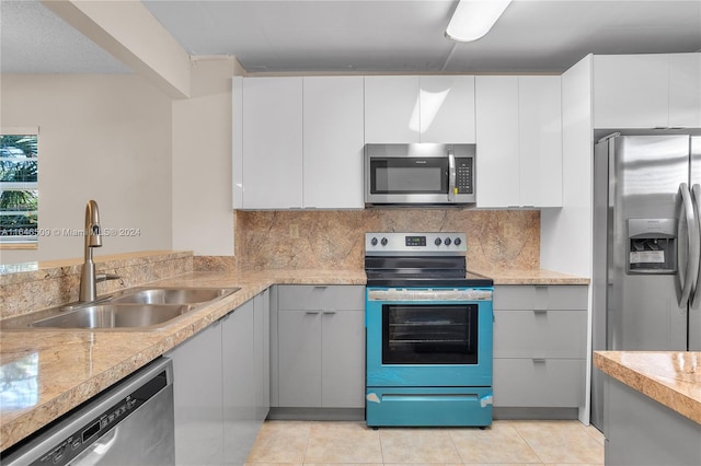 kitchen with light tile patterned floors, sink, stainless steel appliances, and white cabinetry