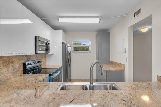 kitchen featuring sink, white cabinetry, light stone countertops, and stainless steel appliances