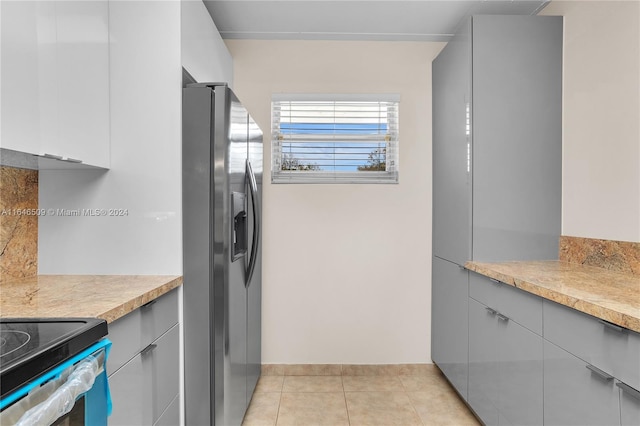 kitchen featuring light tile patterned floors, stainless steel fridge, and gray cabinets