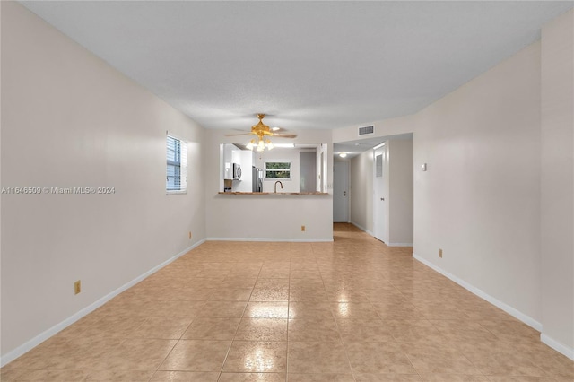 unfurnished room with sink, ceiling fan, light tile patterned flooring, and a textured ceiling