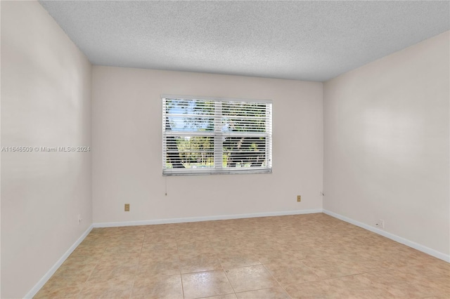 tiled spare room featuring a textured ceiling