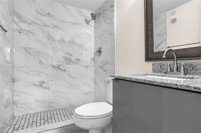 bathroom featuring tiled shower, toilet, and vanity