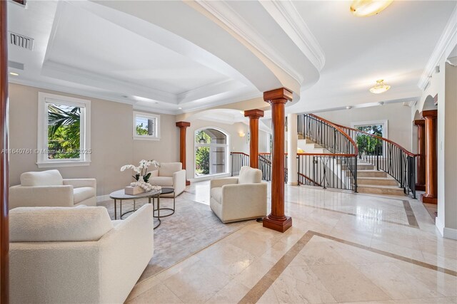 living room featuring decorative columns, ornamental molding, and a tray ceiling