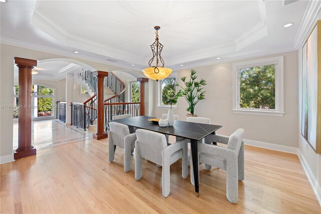 dining room with crown molding, light hardwood / wood-style flooring, and a tray ceiling