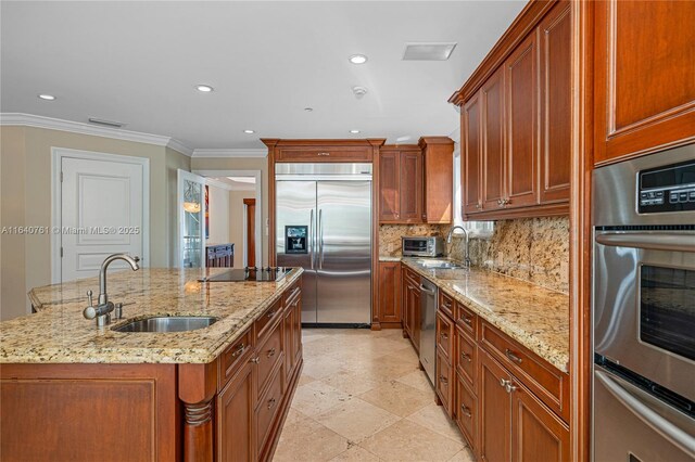 kitchen with stainless steel appliances, light stone countertops, a kitchen island with sink, and sink