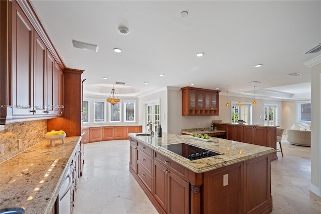 kitchen featuring hanging light fixtures, a tray ceiling, black electric stovetop, a large island, and light stone countertops