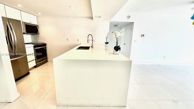 kitchen with sink, white cabinetry, appliances with stainless steel finishes, and light tile patterned floors