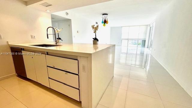 kitchen featuring sink, kitchen peninsula, and light tile patterned floors