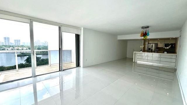 unfurnished living room with light tile patterned floors and a water view