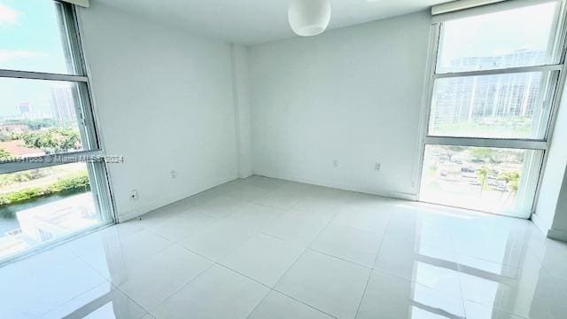 spare room with expansive windows, a healthy amount of sunlight, and light tile patterned floors