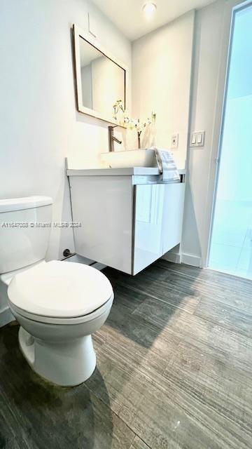 bathroom featuring toilet, hardwood / wood-style floors, and vanity